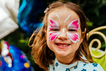 Little Girl Having Her Face Painted For Kids Party. Halloween Or Carnival Family Lifestyle Face Painting, Headshot Close Up