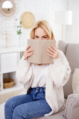 Wall Mural - literature and education concept - cute blond woman covering his face with book in living room