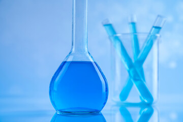 Laboratory beakers, microscope, blue background