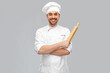 cooking, culinary and people concept - happy smiling male chef or baker in toque with rolling pin over grey background