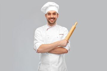 Wall Mural - cooking, culinary and people concept - happy smiling male chef or baker in toque with rolling pin over grey background