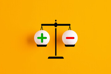 Plus and minus or positive and negative symbols are in balance on a scale.