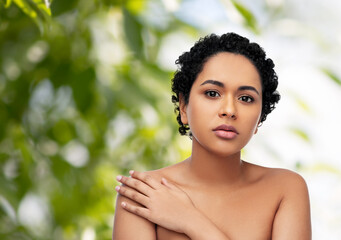 Wall Mural - beauty and people concept - portrait of young african american woman with bare shoulders over green natural background