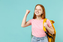Little Overjoyed Pupil Redhead Kid Girl 12-13 Year Old In Pink T-shirt Yellow School Bag Backpack Do Winner Gesture Clench Fist Isolated On Pastel Blue Background Children Lifestyle Childhood Concept.
