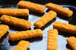 Fish sticks background. Fried fish sticks on a culinary baking sheet as an appetizer and food for children and parties.