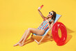 Full body length happy young woman wear red blue swimsuit sit on wooden chair hold use mobile cell phone isolated on vivid yellow color background studio Summer hotel pool sea rest sun tan concept