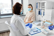 © Syda Productions - health, medicine and pandemic concept - female doctor or nurse wearing protective medical mask and gloves opening package with syringe for vaccination and patient at hospital