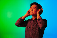 Close-up Asian Young Man Isolated Over Gradient Green Blue Background In Neon Light.