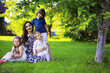 © alexkich - Young large family on a summer morning walk. Beautiful mother with children is playing in the park.