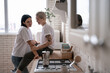 © LIGHTFIELD STUDIOS - happy young woman sitting on kitchen table and hugging with girlfriend near coffee pot on stove