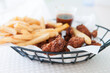 Closeup shot of tasty fry and chicken wings in a metal basket