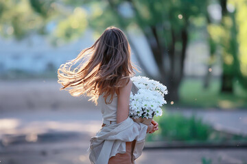 Wall Mural - happy girl with flowers in the city / summer photo young beautiful girl holding a bouquet of flowers
