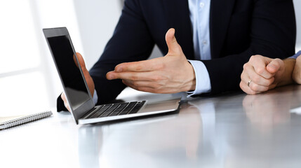 Business people using laptop computer while working together at the desk in modern office. Unknown businessman or male entrepreneur with colleague at workplace. Teamwork and partnership concept