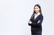 © nut_foto - Asian working female who has long hair wears black formal suit with blue shirt while she arm crossing and smiling happily on white background.