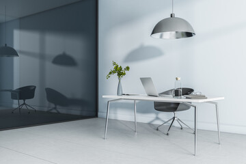 Stylish cold shades workspace at home with laptop and glass bottle on marble tabletop, ceramic tales and black glossy wall