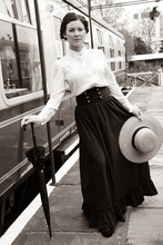 Portrait Of Beautiful Vintage Lady Standing On Platform With Hat And Umbrella