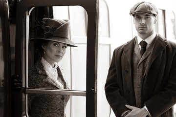 Beautiful woman dressed in vintage 1920s costume arriving by train and greeted by her bodyguard