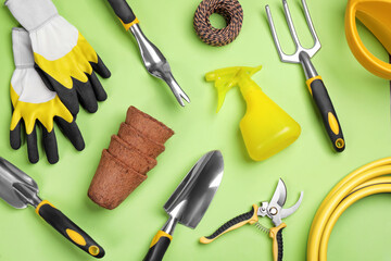 Flat lay composition with gardening tools on green background