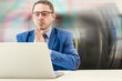© Anoo - handsome adult businessman praying with hands together while looking at laptop screen in office.