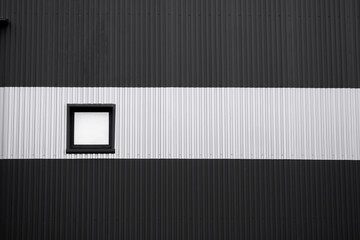 Wall Mural - Black and white corrugated iron sheet used as a facade of a warehouse or factory with a window. Texture of a seamless corrugated zinc sheet metal aluminum facade. Architecture. Metal texture.