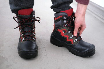 close-up of a pair of new high black work boots made of genuine leather with a reinforced cape on the man's feet, trying on new shoes, the concept of special protective professional shoes