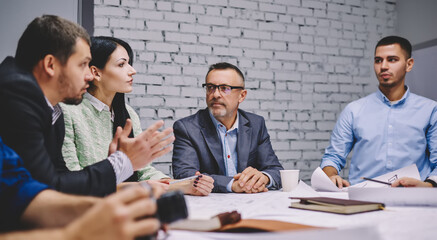 Male and female business persons discussing collaboration and teambuilding during corporate meeting at table desktop, experienced experts talking about strategy planning during working day in firm