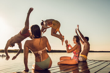 Wall Mural - Friends having fun enjoying a summer day swimming and jumping at the lake.