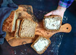 A child's hand holds a piece of bread with butter. Homemade whole grain bread with with seeds