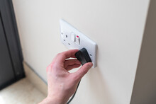 White Uk plug sockets being unplugged to save electricity and money for the household