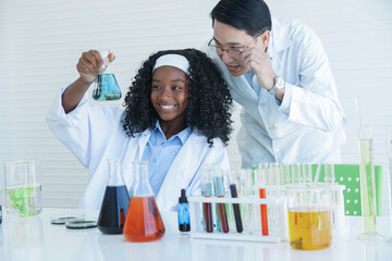 Wall Mural - African American kid scientist and Asian teacher man looking chemical liquid for experiment at laboratory school. White background