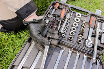 Male hand in construction of a glove with a ratchet taken from a toolbox. Industrial metal tool