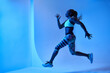 © Manuel Ruiz/ADDICTIVE STOCK - Side view of determined African American female athlete jumping while running and looking forward during training on blue background