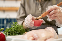 Crop Anonymous Female With Pastry Brush Greasing Raw Poultry With Soybean Sauce While Cooking At Home