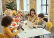 © Kostiantyn - Group of diverse kids working together with young female teacher, sitting at the table during STEM class