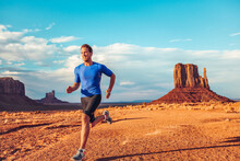 Fitness Athlete Runner Man Sprinting Ultra Running Across Desert Landscape Scenery On Run Trail Marathon Competition Outdoors. Endurance Long Distance Training. Monument Valley, USA.