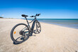 un vélo à assistance électrique sur une plage de sable blanc avec une mer bleue