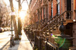 Block of historic brownstone buildings on Charles Street in the West Village neighborhood of New York City with afternoon sunlight shining on the empty sidewalk with no people