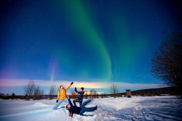 company of friends tourist looks aurora northern lights night at forest, soft focus