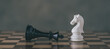 © Looker_Studio - Chess Pieces on Board for Game and Strategy concept. White Chess Knight among lying down black king on chessboard.
