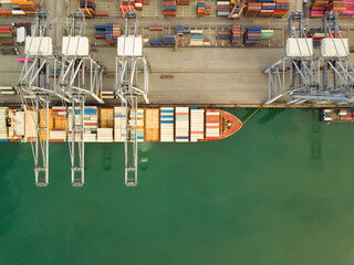 Wall Mural - Aerial drone view above dockyard. Cargo vessel is loading containers. Professional business logistics and transportation of cargo ship.