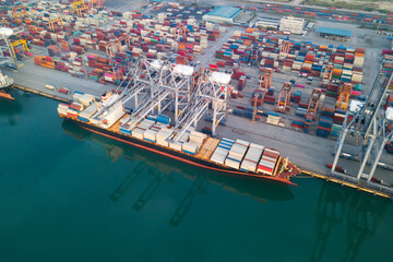 Wall Mural - Aerial drone view above dockyard. Cargo vessel is loading containers. Professional business logistics and transportation of cargo ship.