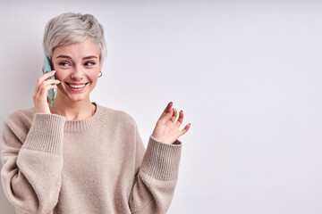 Portrait of cute caucasian woman communicating with someone on smartphone, have talk, discussing, short haired lady looking at side, smiling, dressed casually, isolated on white studio background