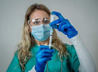 Female doctor or nurse holding COVID-19 Vaccine. Coronavirus medical treatment.