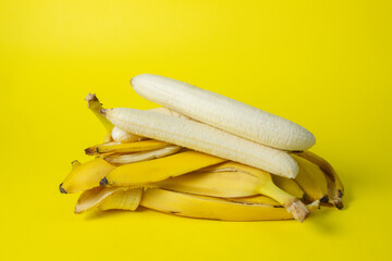 Poster - Bananas on a yellow background. Bright fruits. Peeled bananas on a bunch of banana peels.