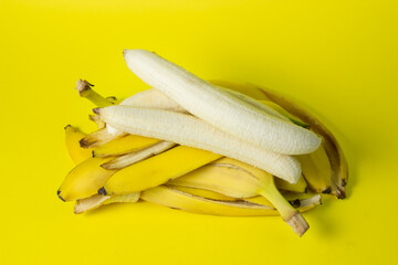 Poster - Bananas on a yellow background. Bright fruits. Peeled bananas on a bunch of banana peels.