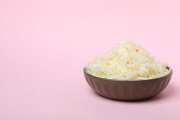 Bowl of sauerkraut on pink background, space for text