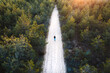 © AmazingAerialAgency - Aerial view of person walking on sandy road in the middle of young forest during golden Spring sunset in Uzusaliai, Kaunas, Lithuania.