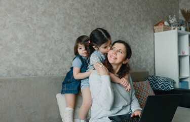 mom works at home on the computer surrounded by small children