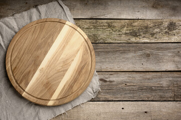 Wall Mural - empty round wooden cutting kitchen board on wooden background, pizza board, top view