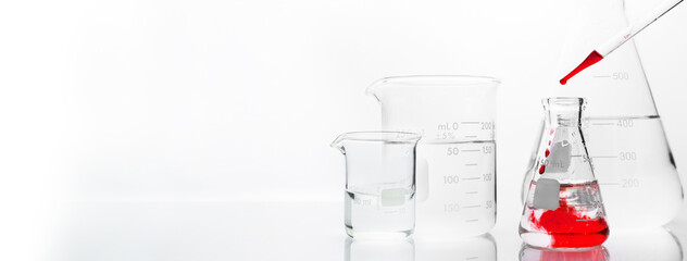 Wall Mural - glass flask and beaker with orange drop solution in chemistry science research lab white banner back